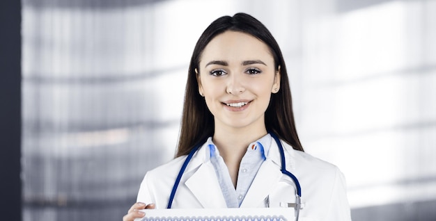 Glückliche junge ärztin hält ein zertifikat in ihren händen. professioneller arzt bei der arbeit in einer klinik. medizin-konzept.