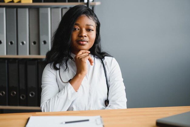 Glückliche junge afrikanische Krankenschwester, die im Büro arbeitet