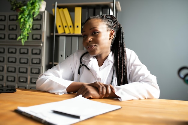 Glückliche junge afrikanische Krankenschwester, die im Büro arbeitet