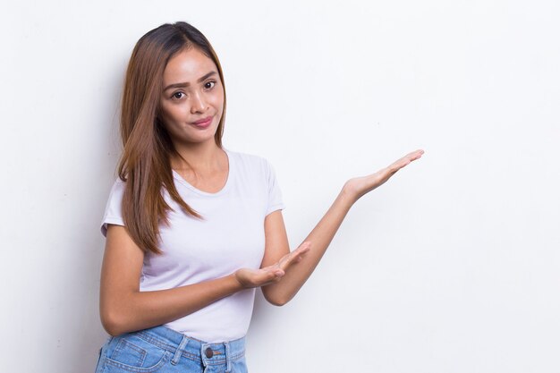 Glückliche junge asiatische Frau zeigt mit den Fingern in verschiedene Richtungen isoliert auf weißem Hintergrund