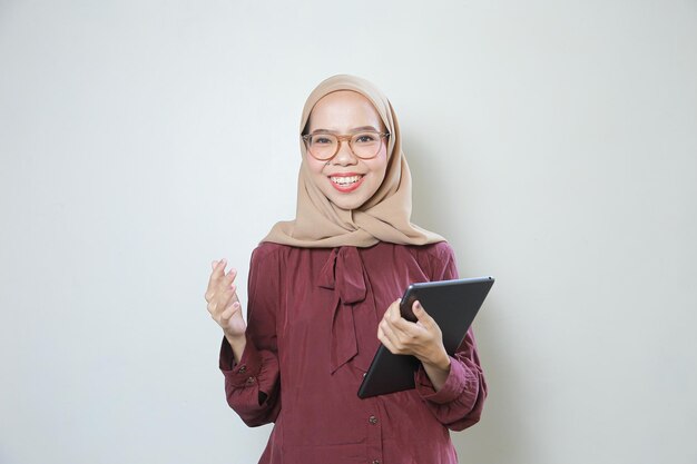 Glückliche junge asiatische muslimische Frau mit Tablet über isoliertem weißem Hintergrund