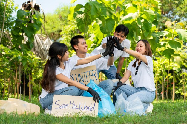 Glückliche junge asiatische Studenten, diverse Freiwillige halten ein Kampagnenschild für die Reinigung des Parks