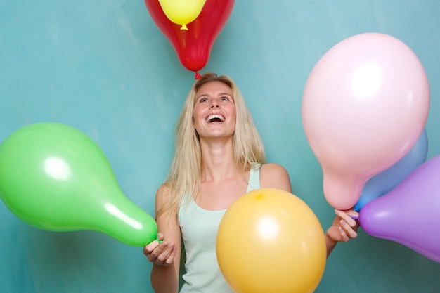 Glückliche junge blonde Frau, die mit Ballonen spielt