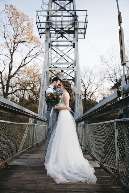 Glückliche junge Braut und Bräutigam auf einer Hängebrücke