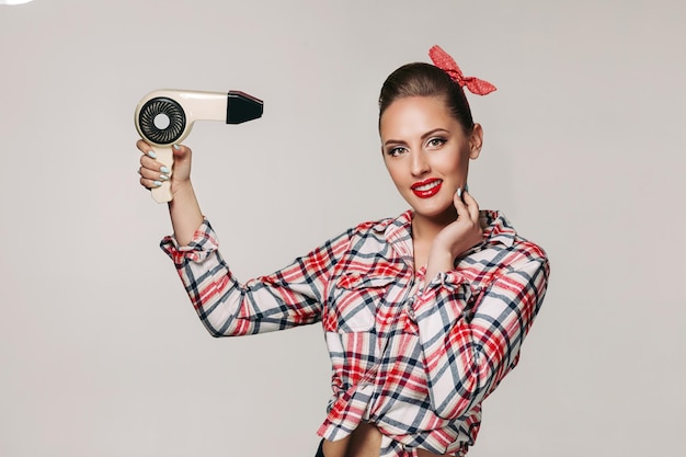 Glückliche junge Brunettefrau mit Haartrockner