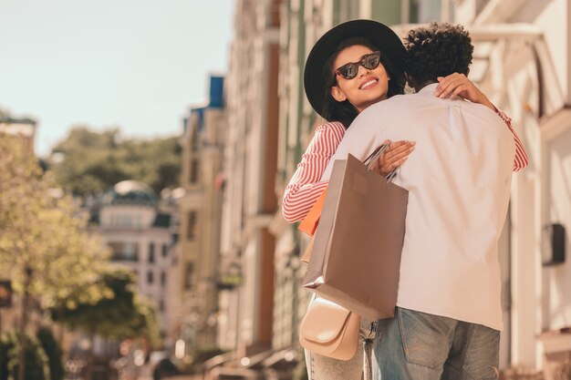 Glückliche junge Dame mit Papiertüten, die einen Mann lächelt und umarmt. Website-Banner