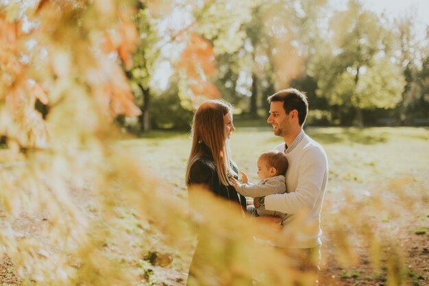 Glückliche junge Eltern mit Baby im Herbstpark