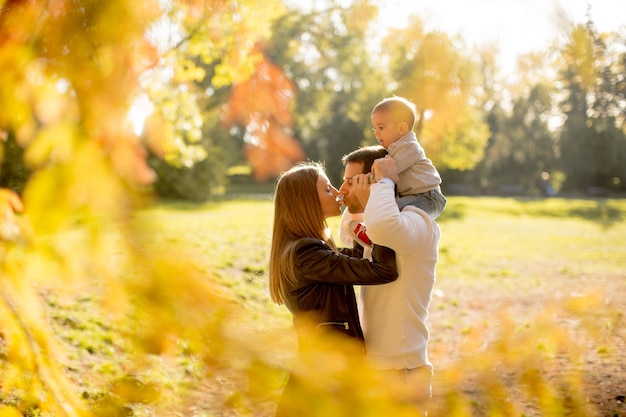 Glückliche junge Eltern mit Baby im Herbstpark