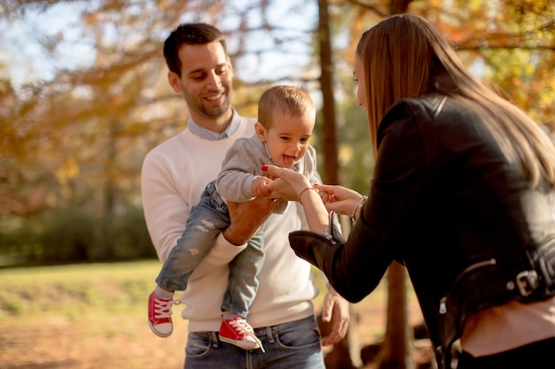 Glückliche junge Eltern mit Baby im Herbstpark