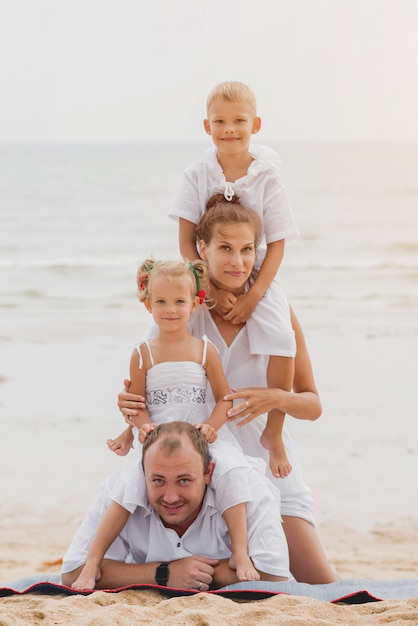 Glückliche junge Familie auf dem Sonnenuntergang am Strand.