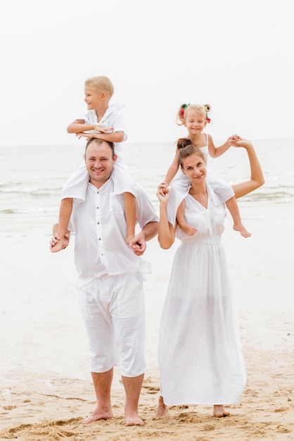 Glückliche junge Familie auf dem Sonnenuntergang am Strand.