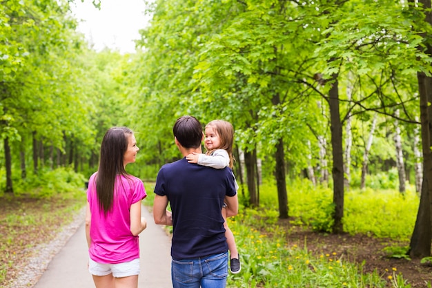 Glückliche junge familie, die die straße draußen in der grünen natur geht.