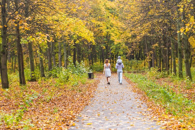 Glückliche junge Familie, die die Straße draußen in der grünen Natur geht