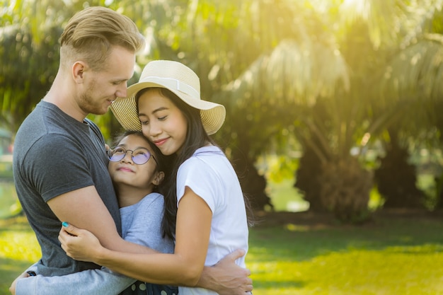 Glückliche junge Familie, die im Park umarmt