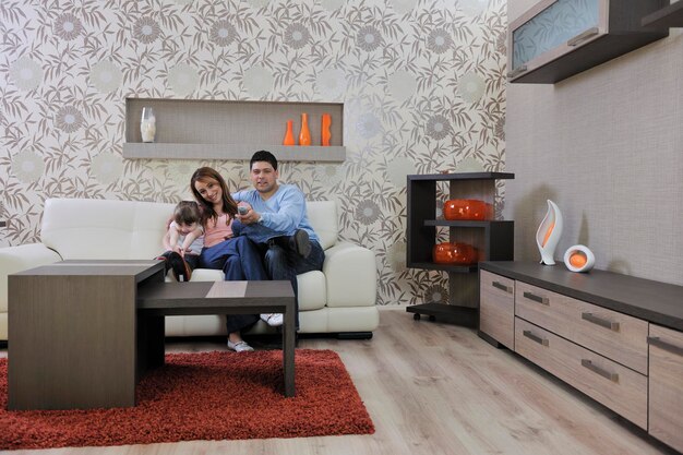 glückliche junge familie, die sich zu hause im modernen wohnzimmer entspannt