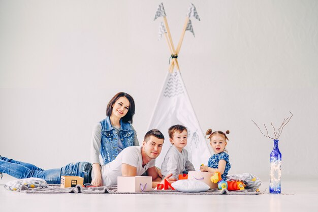 Glückliche junge Familie, die Spaß im weißen Kinderzimmer hat. Mutter, Vater, Schwester und Bruder spielen zusammen.