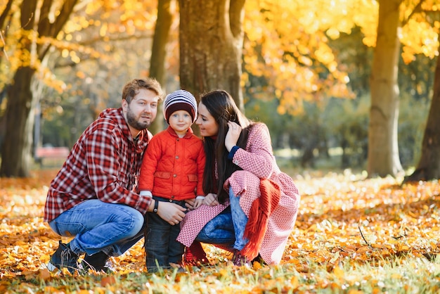 Glückliche junge Familie, die Zeit im Freien im Herbstpark verbringt