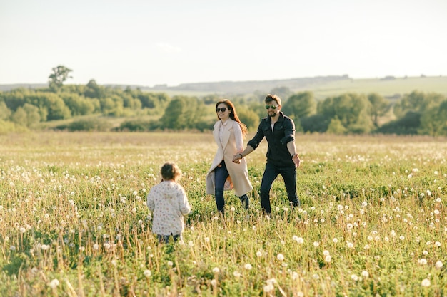 Glückliche junge Familie, die Zeit zusammen draußen in der grünen Natur verbringt.