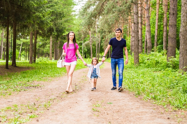 Glückliche junge Familie, die zusammen Zeit draußen in der grünen Natur verbringt.