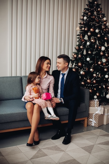 Foto glückliche junge familie feiert neues jahr zusammen nahe dem weihnachtsbaum