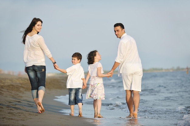 glückliche junge familie hat spaß am strandlauf und springt bei sonnenuntergang