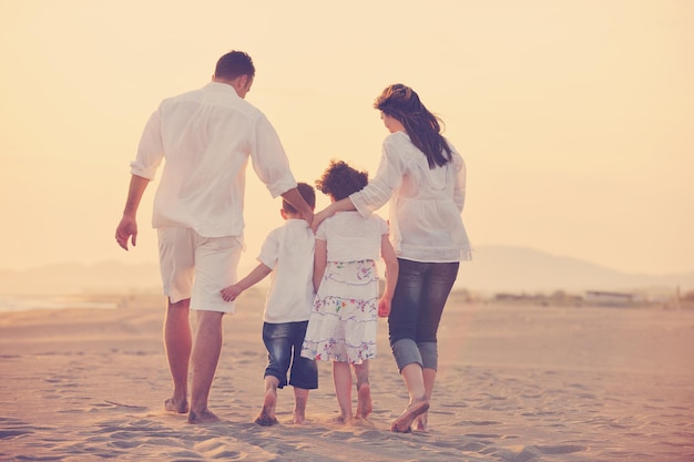 glückliche junge familie hat spaß am strandlauf und springt bei sonnenuntergang