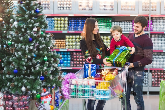 Glückliche junge Familie im Supermarkt wählt Geschenke für christmass