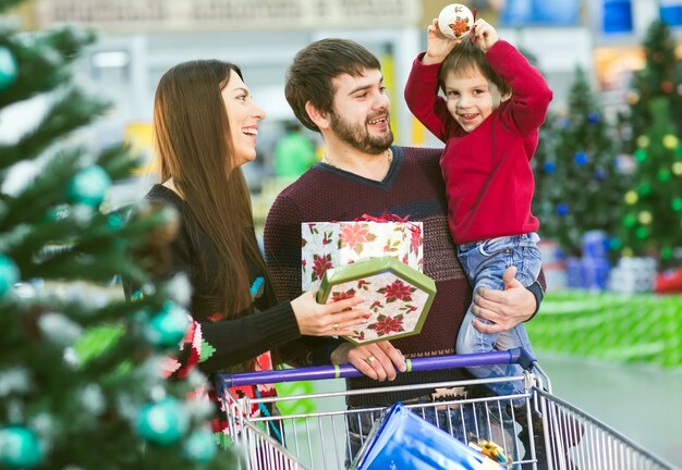 Glückliche junge Familie im Supermarkt wählt Geschenke für das neue Jahr.