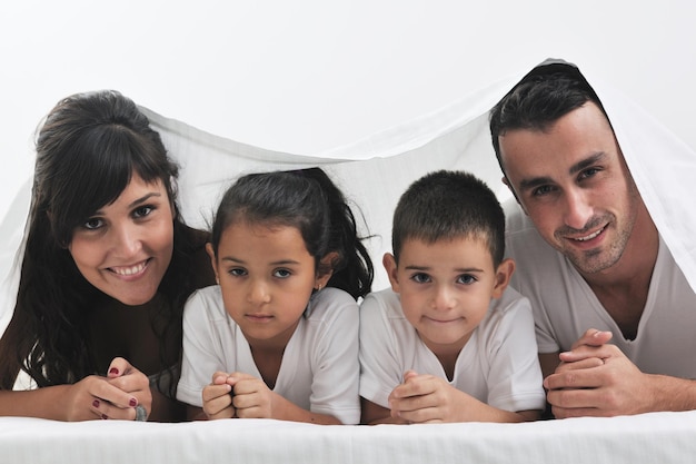 glückliche junge Familie in ihrem Schlafzimmer hat Spaß und spielt im Bett