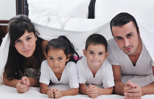 glückliche junge Familie in ihrem Schlafzimmer hat Spaß und spielt im Bett