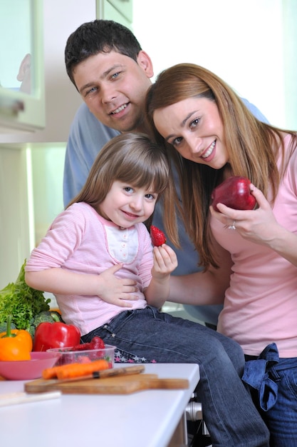 glückliche junge familie isst mittagessen mit frischem obst und gemüse in der hellen küche