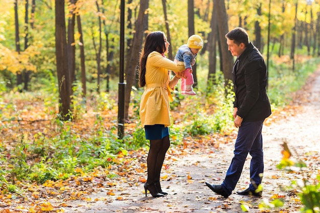 glückliche junge Familie mit ihrer Tochter, die Zeit draußen im Herbstpark verbringt