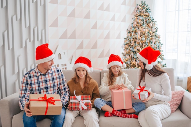 Glückliche junge Familie mit Kindern, die Weihnachtsgeschenke halten