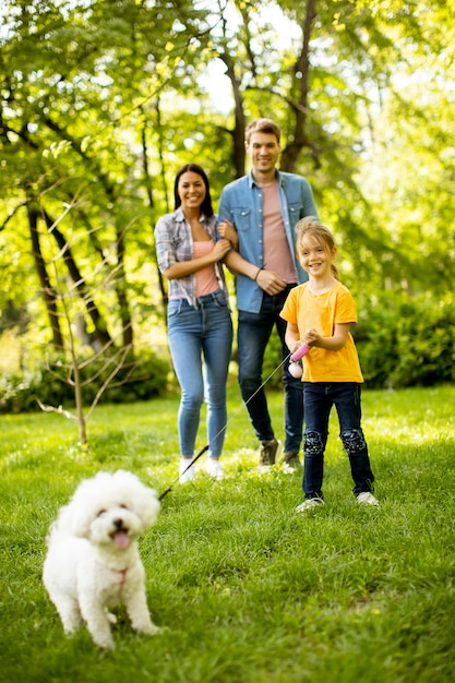 Glückliche junge Familie mit niedlichem Bichonhund im Park