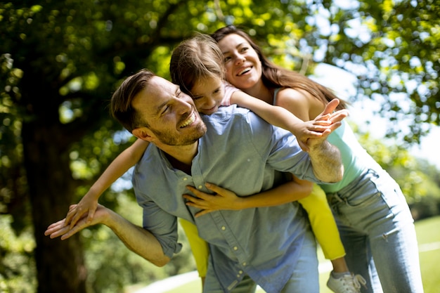 Glückliche junge Familie mit süßer kleiner Tochter, die an einem sonnigen Tag Spaß im Park hat