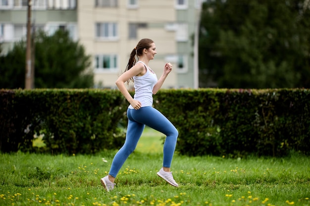 Glückliche junge Frau beim morgendlichen Joggen im Stadtpark