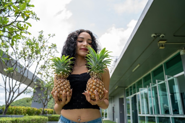 Glückliche junge Frau, die Ananas zeigt Ananas-Obst-Frau, die gesund und fröhlich lächelt Mixedrace asiatischen kaukasischen Modell mit Ananas