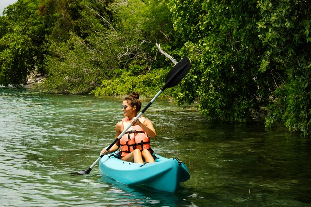 Glückliche junge Frau, die auf dem See Kajak fährt