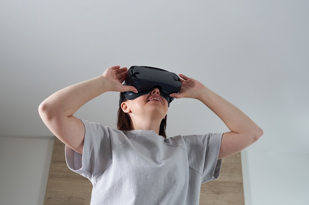 Glückliche junge Frau, die auf VR-Brille innen spielt, virtuelles Realitätskonzept mit jungem Mädchen, das Spaß mit Headsetbrille hat