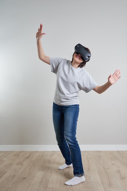 Glückliche junge Frau, die auf VR-Brille innen spielt, virtuelles Realitätskonzept mit jungem Mädchen, das Spaß mit Headsetbrille hat