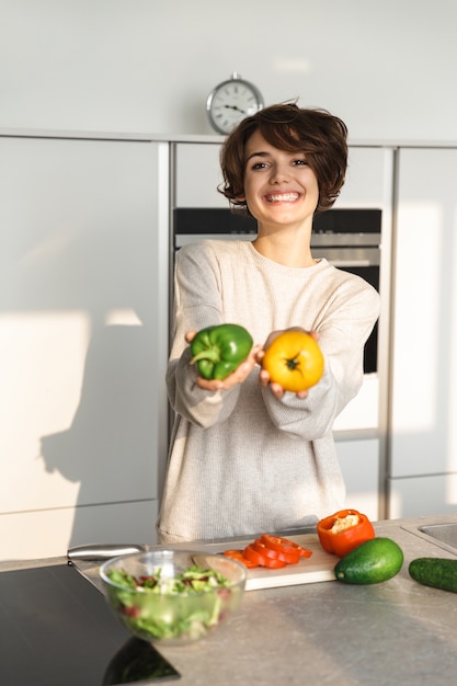 Glückliche junge Frau, die frischen Salat an der Küche zu Hause kocht