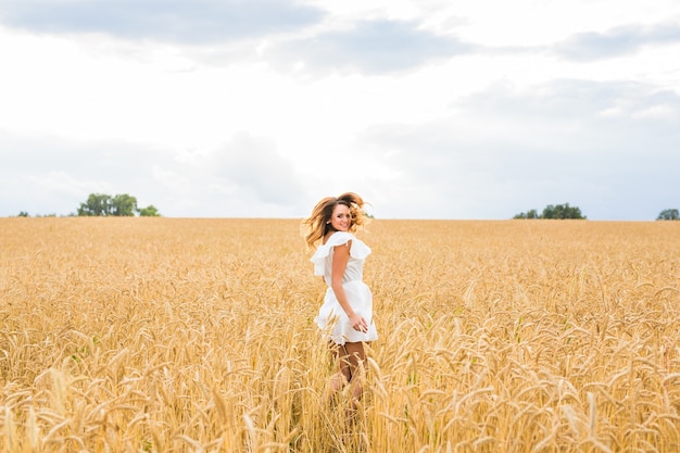 Glückliche junge Frau, die in goldenen Weizen springt.