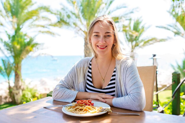 Glückliche junge Frau, die italienische Pasta im Restaurant isst Attraktive Frauen, die am Tisch im Café im Freien mit zubereiteten Speisen und Getränken sitzen, haben Frühstück, Mittag- oder Abendessen, serviert am Tisch