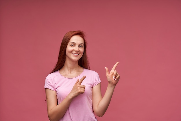 Glückliche junge Frau, die mit ihrem Finger lokalisiert steht