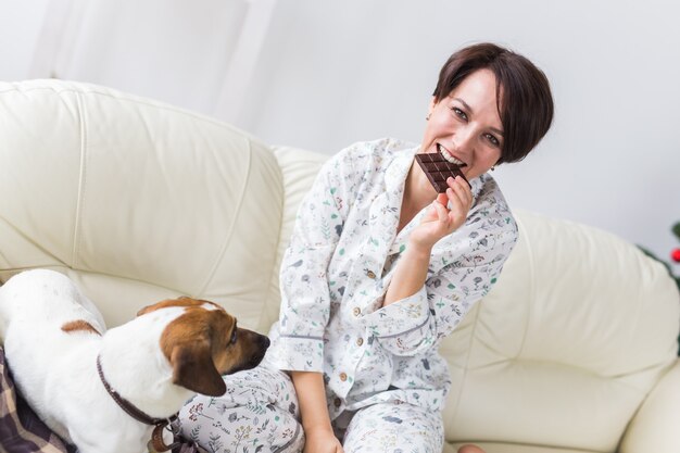 Glückliche junge Frau, die Pyjama im Wohnzimmer mit Weihnachtsbaum trägt