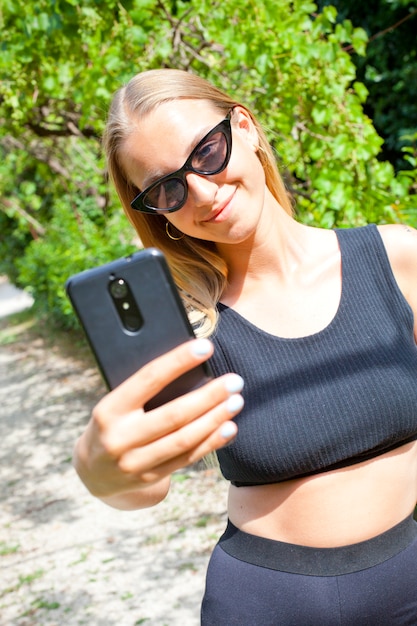 Foto glückliche junge frau, die selfie auf dem alten stadtpark nimmt