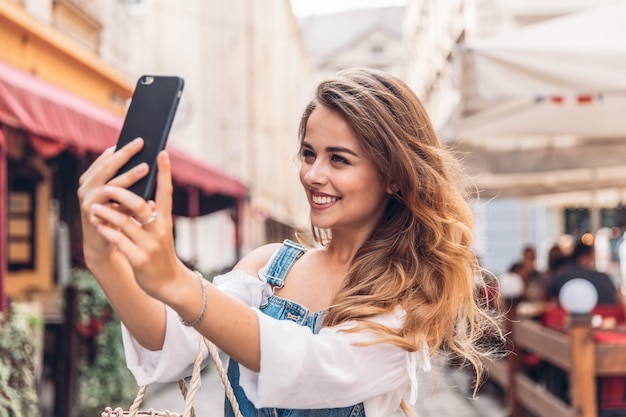 Glückliche junge Frau, die selfie nimmt. Frau, die selfie Foto mit einem smarphone in der Stadt nimmt