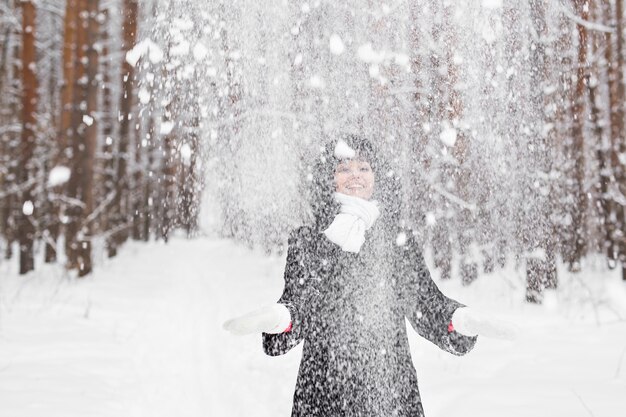 Glückliche junge Frau, die Spaß im Schnee hat.