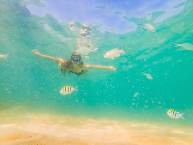 Glückliche junge Frau, die unter Wasser im tropischen Ozean schwimmt