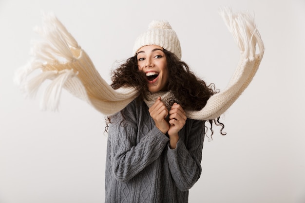 Foto glückliche junge frau, die winterkleidung trägt, die lokal über weißer wand, bewegung steht